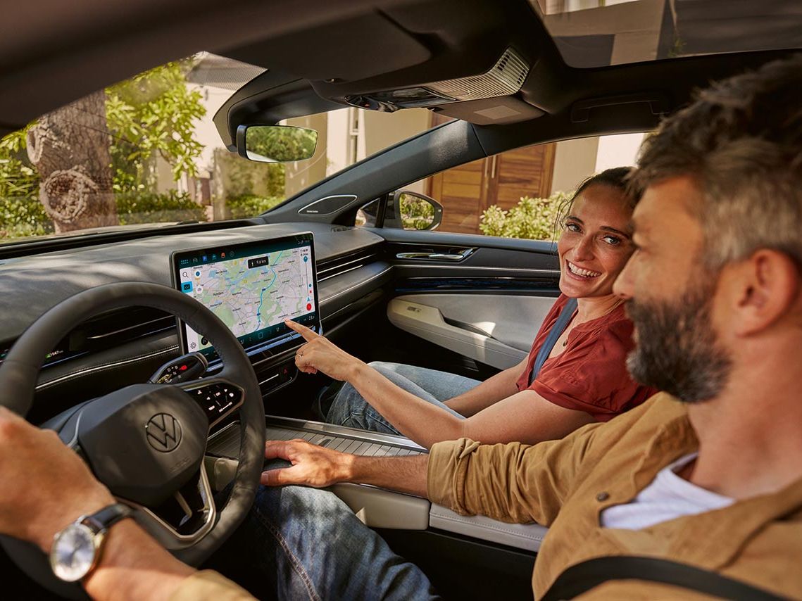 Mann und Frau sitzen im VW ID.7 und blicken auf das Display