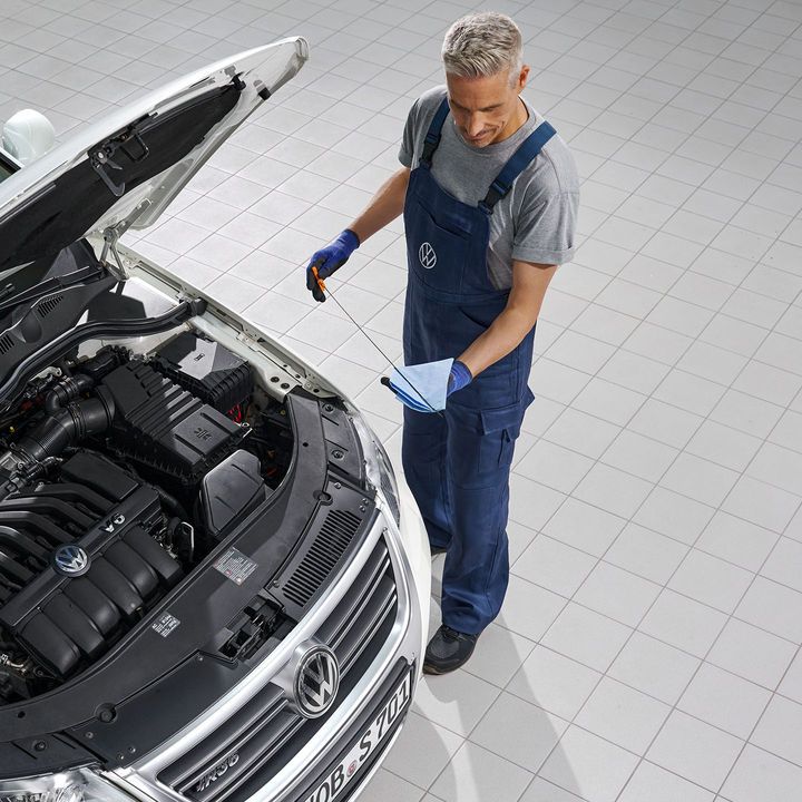 Ein Volkswagen Mechaniker wechselt Öl bei einem weißen Volkswagen Passat.