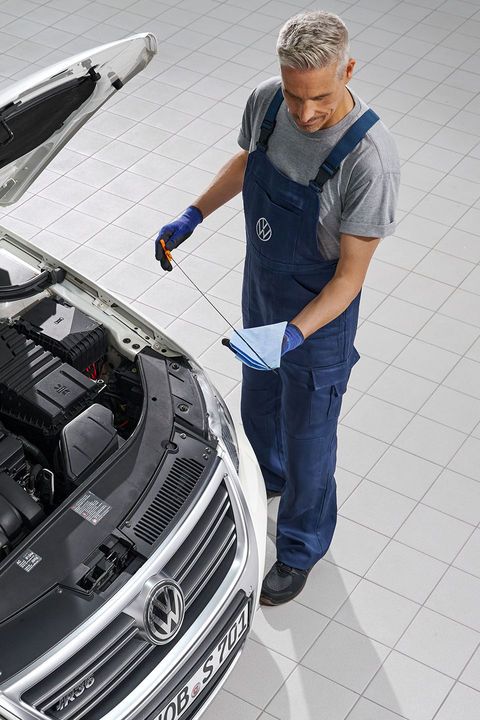 Ein Volkswagen Mechaniker wechselt Öl bei einem weißen Volkswagen Passat.