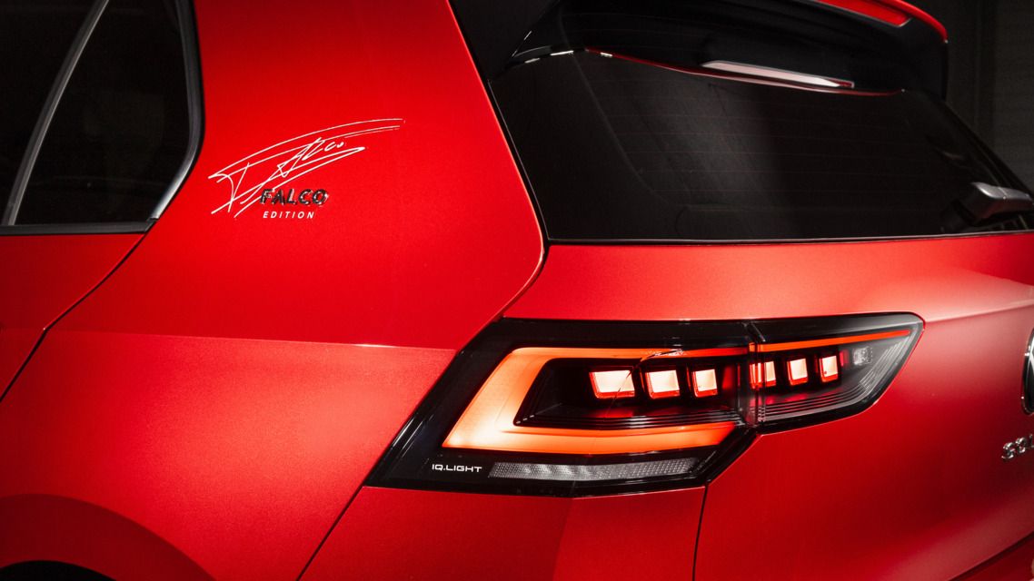 Detailaufnahme des Hecks eines roten VW Golf Falco Edition. Auf der C-Säule ist die Unterschrift von Falco zu sehen.