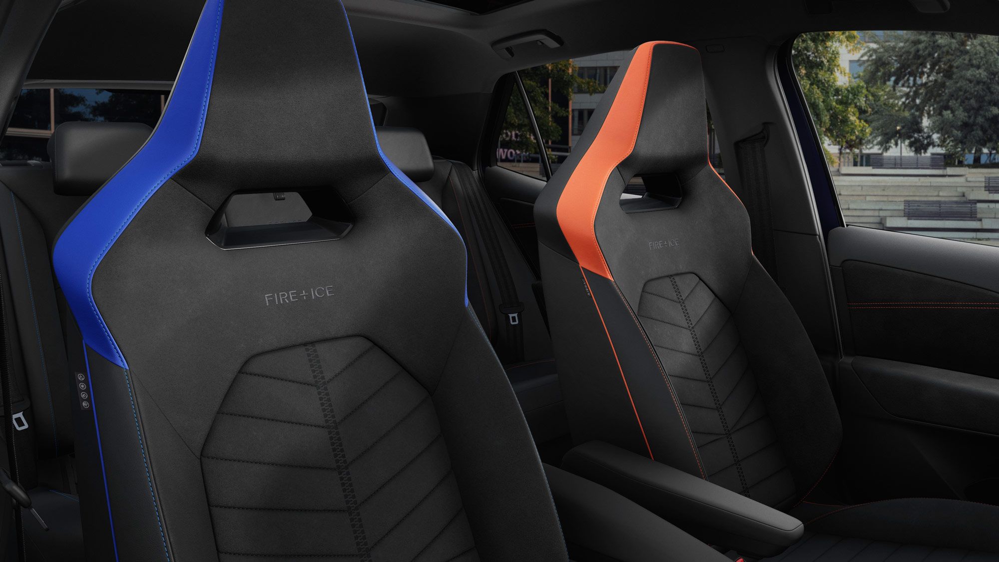 Zwei Rennsportsitze im ID.3 GTX FIRE+ICE, einer ist blau und der andere ist orange. Beide Sitze haben stilvolle Nähte und sind für Komfort und Unterstützung entworfen. Im Hintergrund sind Bäume und Gebäudestrukturen sichtbar.