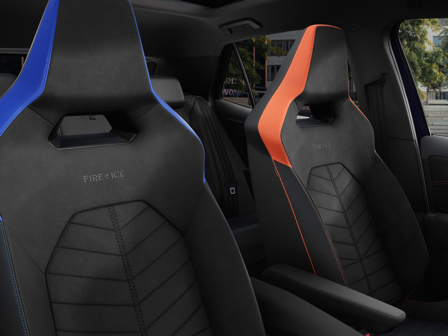 Zwei Rennsportsitze im ID.3 GTX FIRE+ICE, einer ist blau und der andere ist orange. Beide Sitze haben stilvolle Nähte und sind für Komfort und Unterstützung entworfen. Im Hintergrund sind Bäume und Gebäudestrukturen sichtbar.