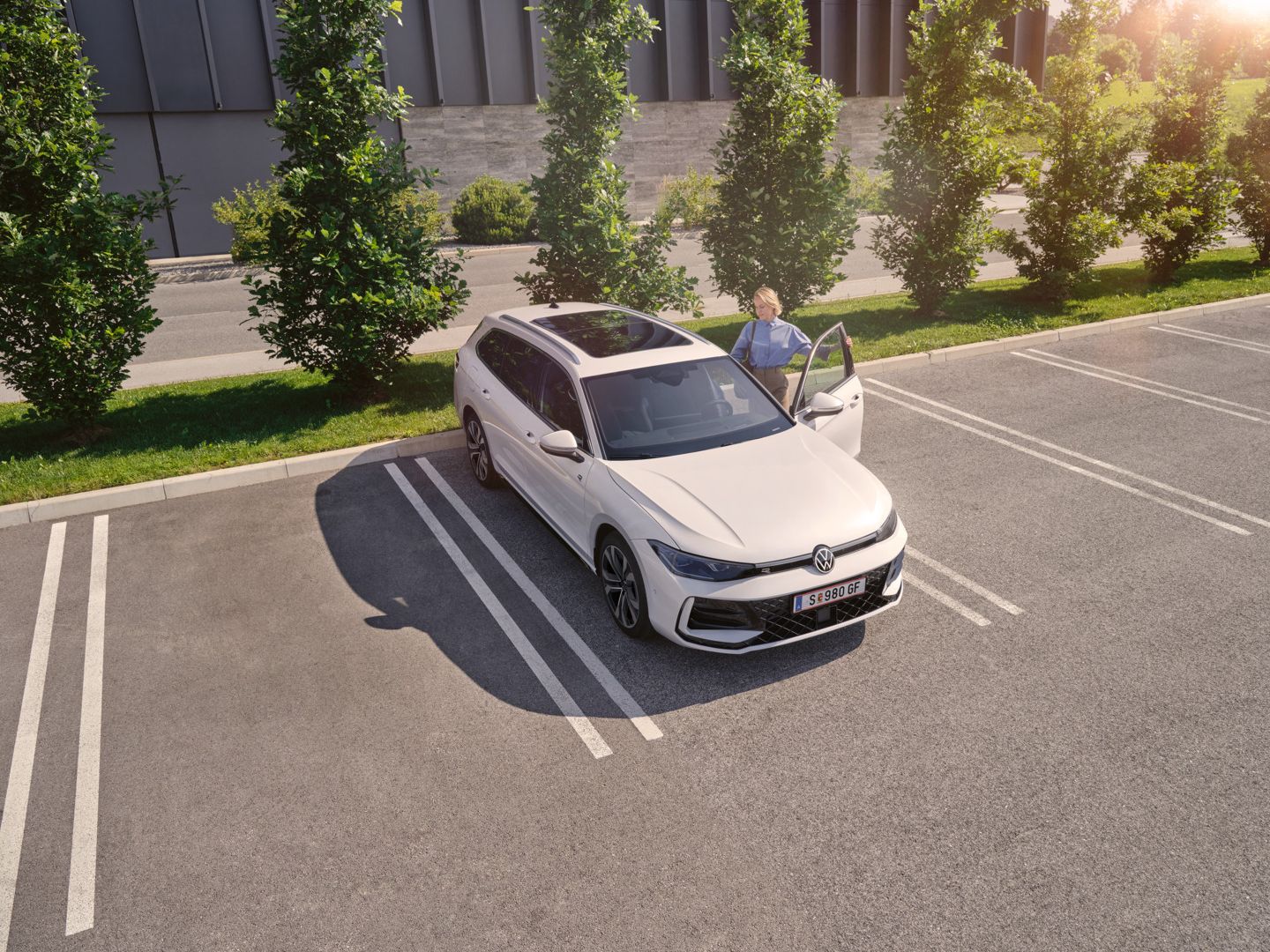 Weißer VW Passat parkt vor einem modernen Bürogebäude. Eine Frau steigt ein.