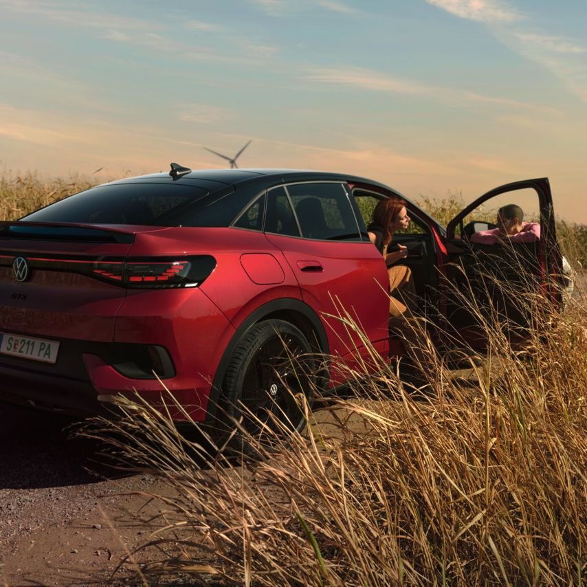 Zwei Personen unterhalten sich neben einem roten ID.5 GTX auf einer Landstraße