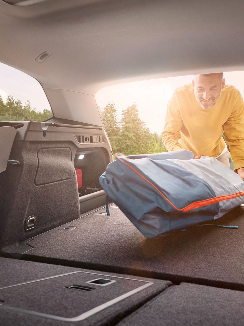 Ein Mann lädt Gepäck in den Laderaum des VW Passat mit umgeklappter Rückbank.