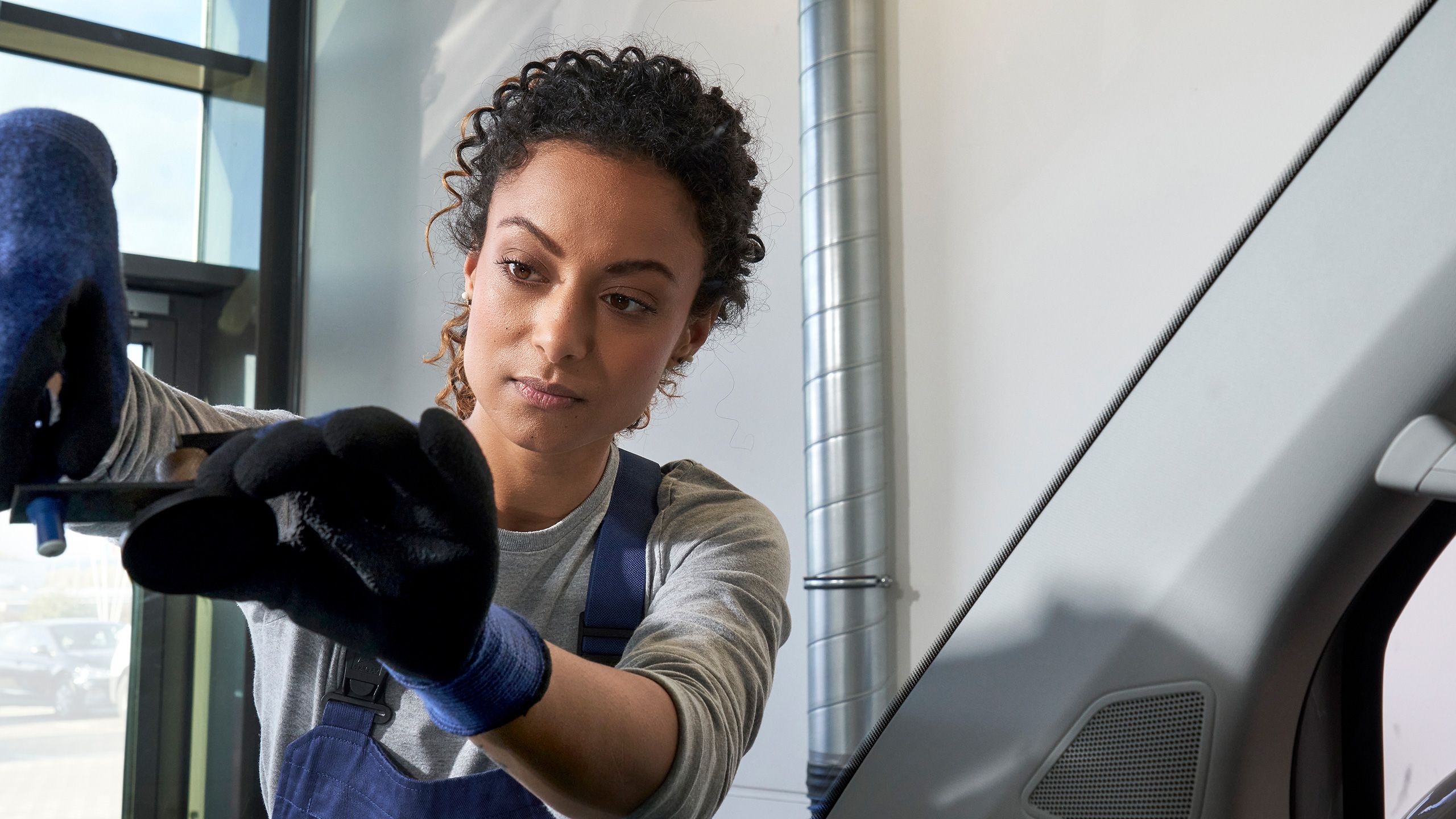 Eine Volkswagen Technikerin repariert den Steinschlag bei einer Windschutzscheibe.