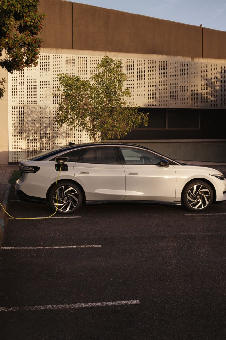 Ein weißer VW ID.7 Pro wird an einer Ladestation geladen.