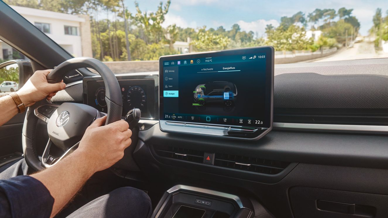 Multifunktionslenkrad und Infotainmentsystem im VW T-Roc Hybrid, Person lenkt das Fahrzeug.