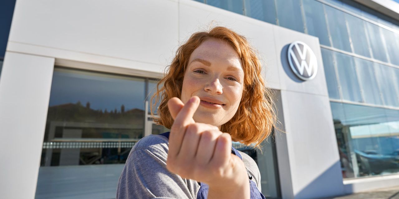 Volkswagen Service Mitarbeiterin vor dem Eingang zu einem Volkswagen Service Partner