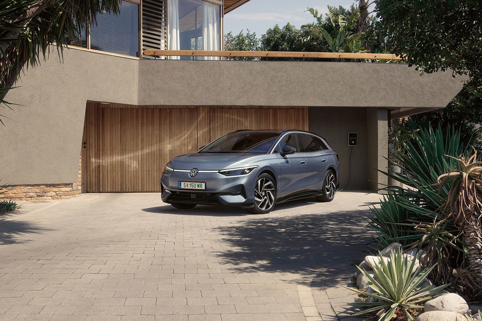 ID.7 Tourer steht geparkt vor einem modernen Haus in einer Einfahrt in Frontansicht. 