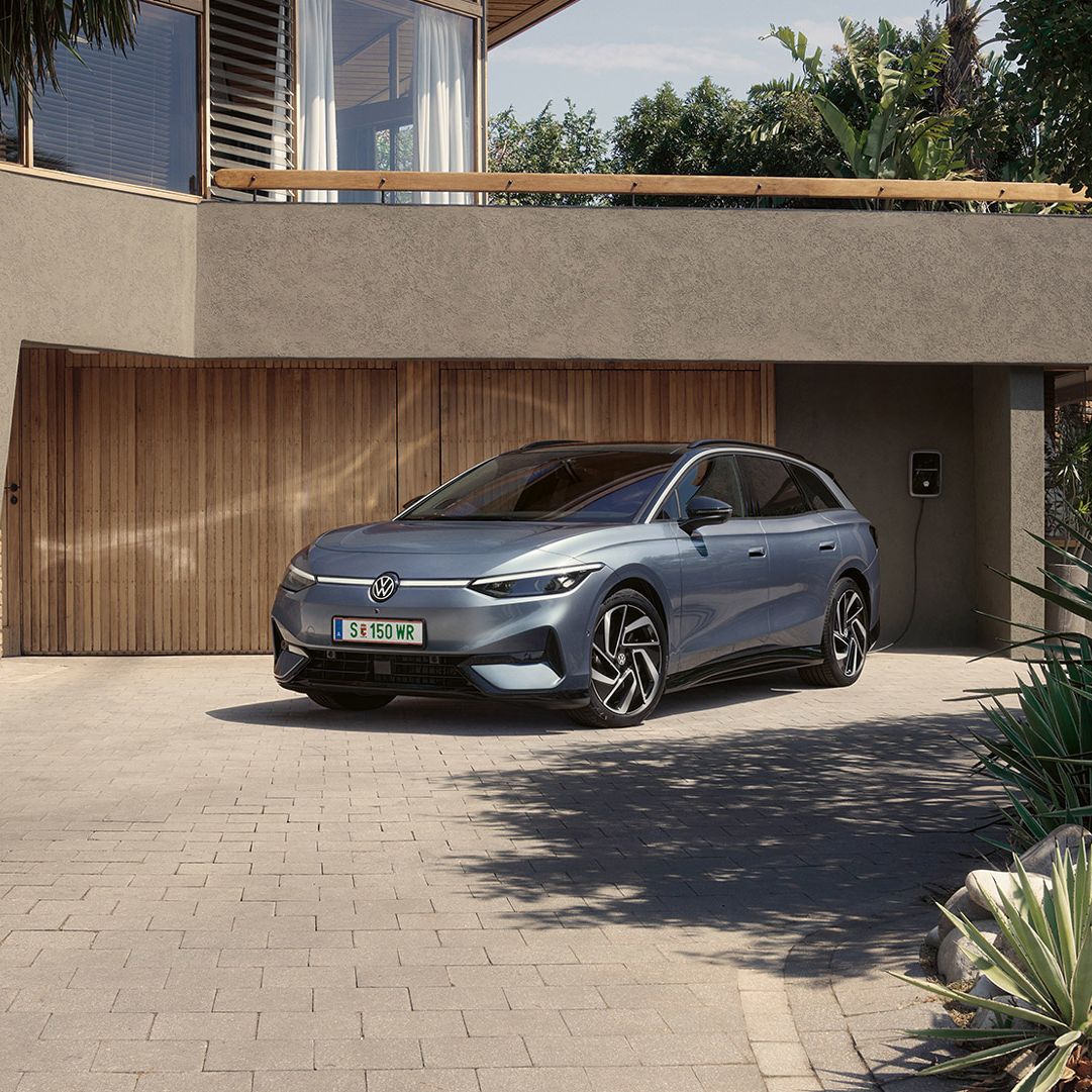 ID.7 Tourer steht geparkt vor einem modernen Haus in einer Einfahrt in Frontansicht. 