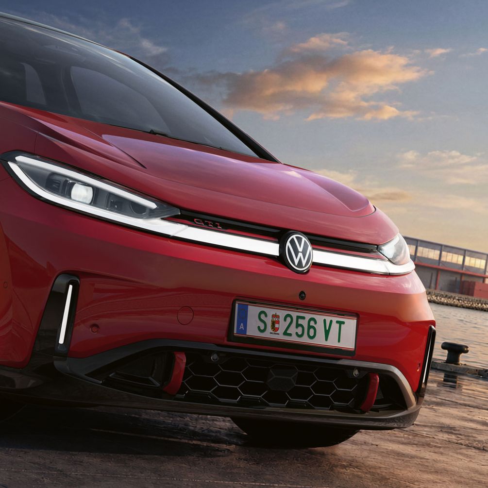 [AI-modified] – Detailansicht der Front eines geparkten roten VW ID.3 GTI mit eingeschalteten Scheinwerfern und beleuchtetem Logo.
