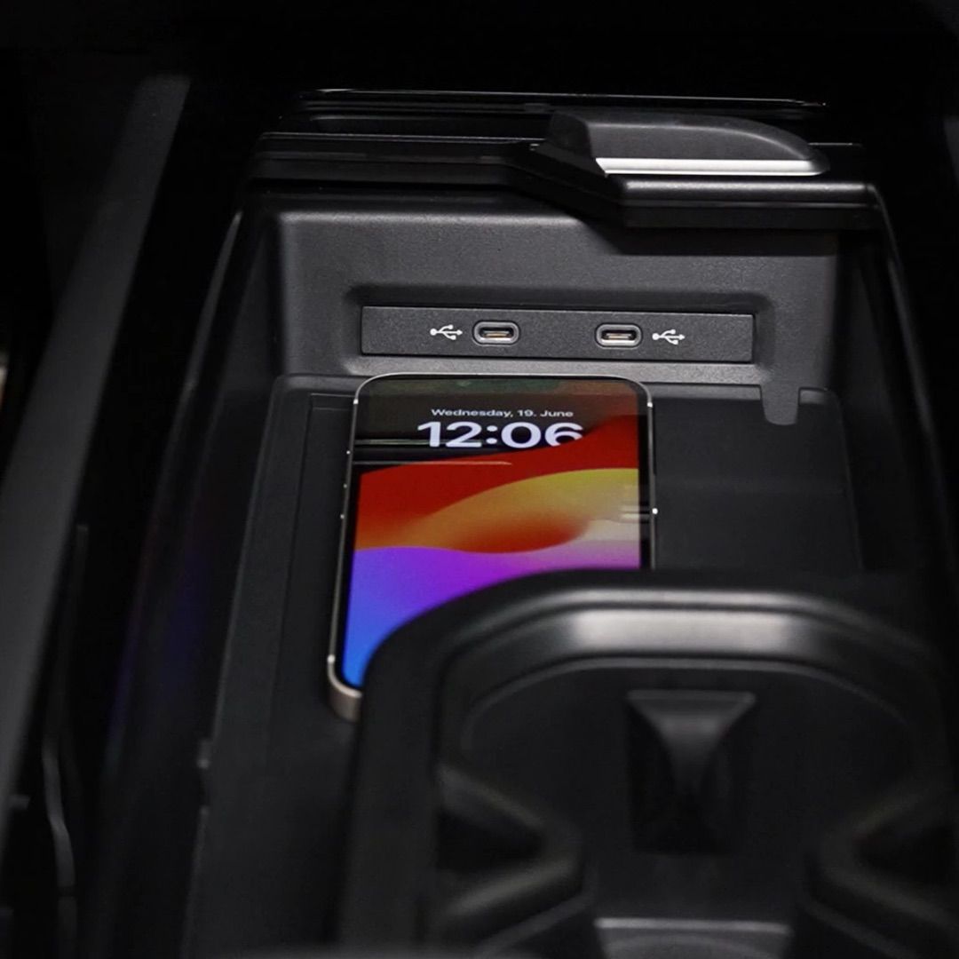 Ein Smartphone liegt auf einem Ladepad in einem Auto. Das Display zeigt die Uhrzeit 12:06 und das Datum Mittwoch, 10. Juni an. Oben sind zwei USB-Anschlüsse sichtbar.