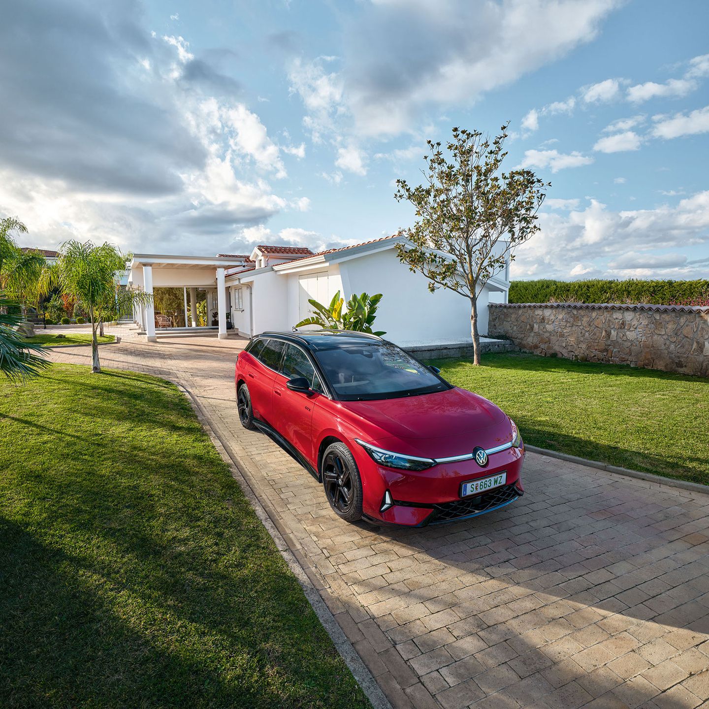 Ein roter VW ID.7 Tourer GTX schräg von vorne vor einem Haus