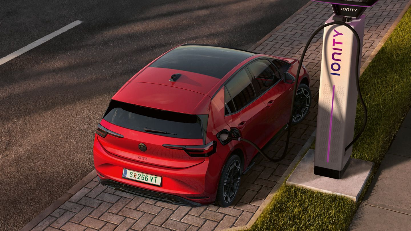 [AI-modified] – Blick von schräg oben auf den ID.3 GTI, welcher gerade am Seitenstreifen an einer Ladesäule angesteckt ist.