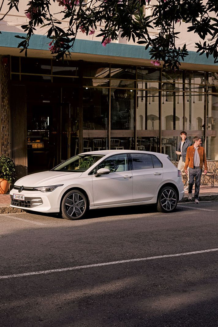 Geparkter VW Golf mit 2 Personen, welche die Straße queren möchten.