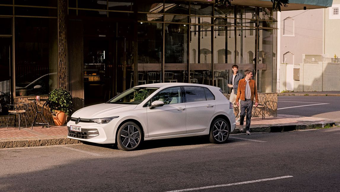 Geparkter VW Golf mit 2 Personen, welche die Straße queren möchten.