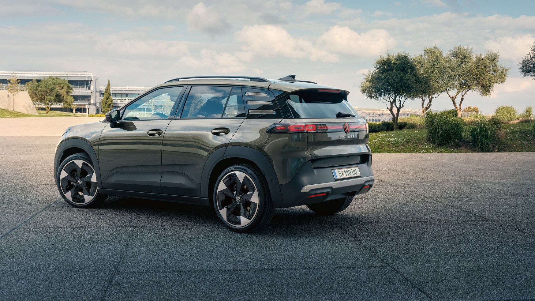 Heckansicht eines grünen VW ID. Cross, der auf einem Platz mit grünen Bäumen parkt.