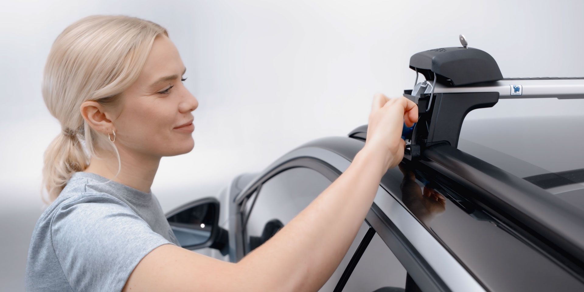 Eine Frau beim befestigen eines Volkswagen Dachträgers.