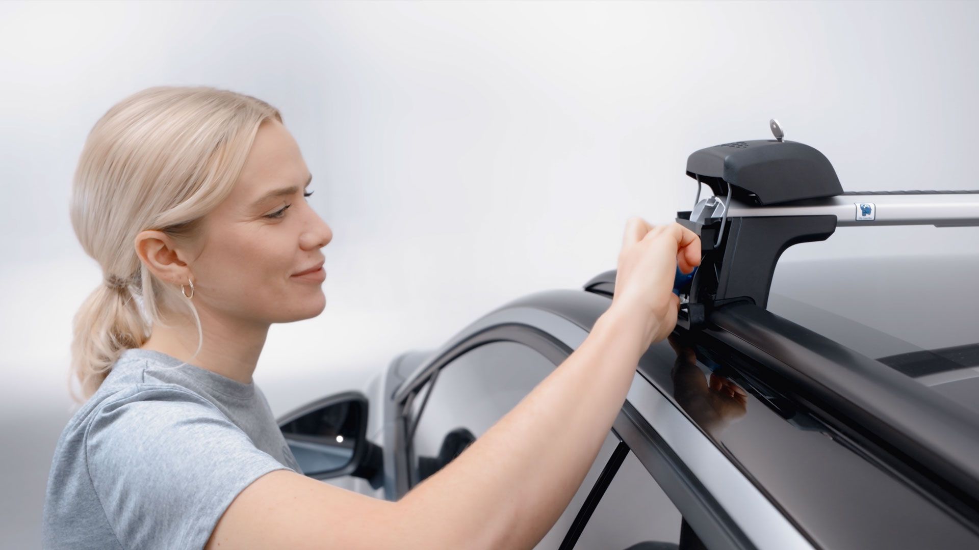 Eine Frau beim befestigen eines Volkswagen Dachträgers.