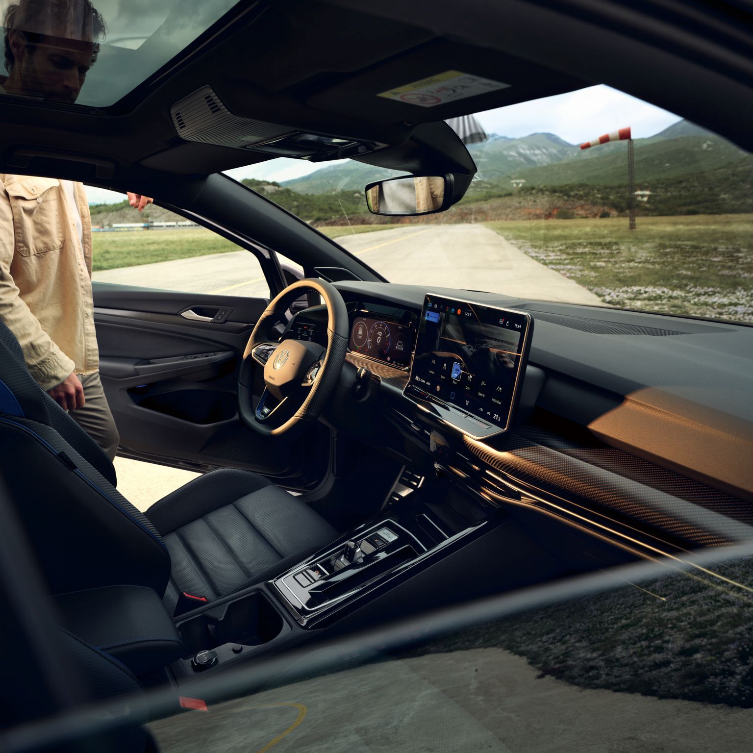 Sicht von Beifahrerfenster aus in das Interior, Mann steigt gerade bei geöffneter Fahrertür in den Golf R.