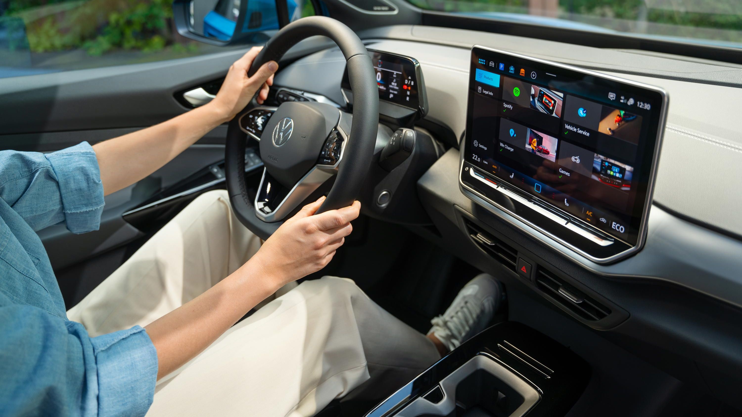 Lenkrad und Infotainment-System im VW ID.4, eine Frau sitzt auf dem Fahrersitz.