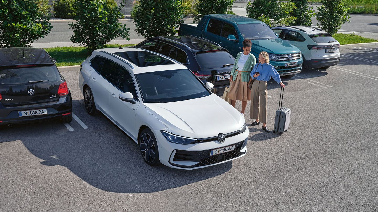 Zwei Frauen stehen auf einem Parkplatz neben einem weißen VW Passat B9