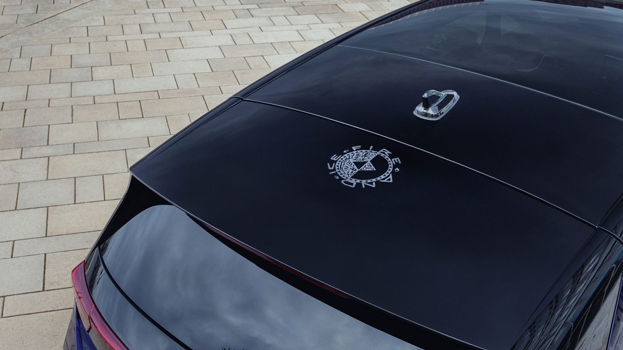 Ein lilanes Auto Auto, dessen Dach mit einem stilisierten Emblem bedruckt ist. Das Emblem zeigt ein Kreis-Symbol und die Worte "Fire" und "Ice". Die glänzende Oberfläche reflektiert die umliegende Umgebung.