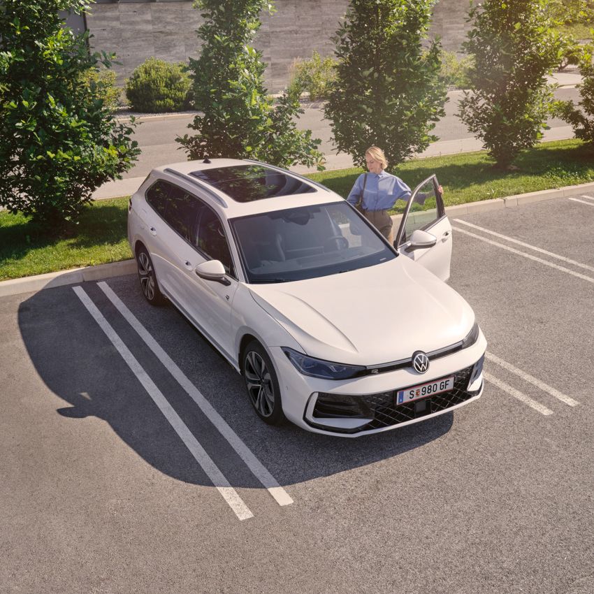 Weißer VW Passat parkt vor einem modernen Bürogebäude. Eine Frau steigt ein.