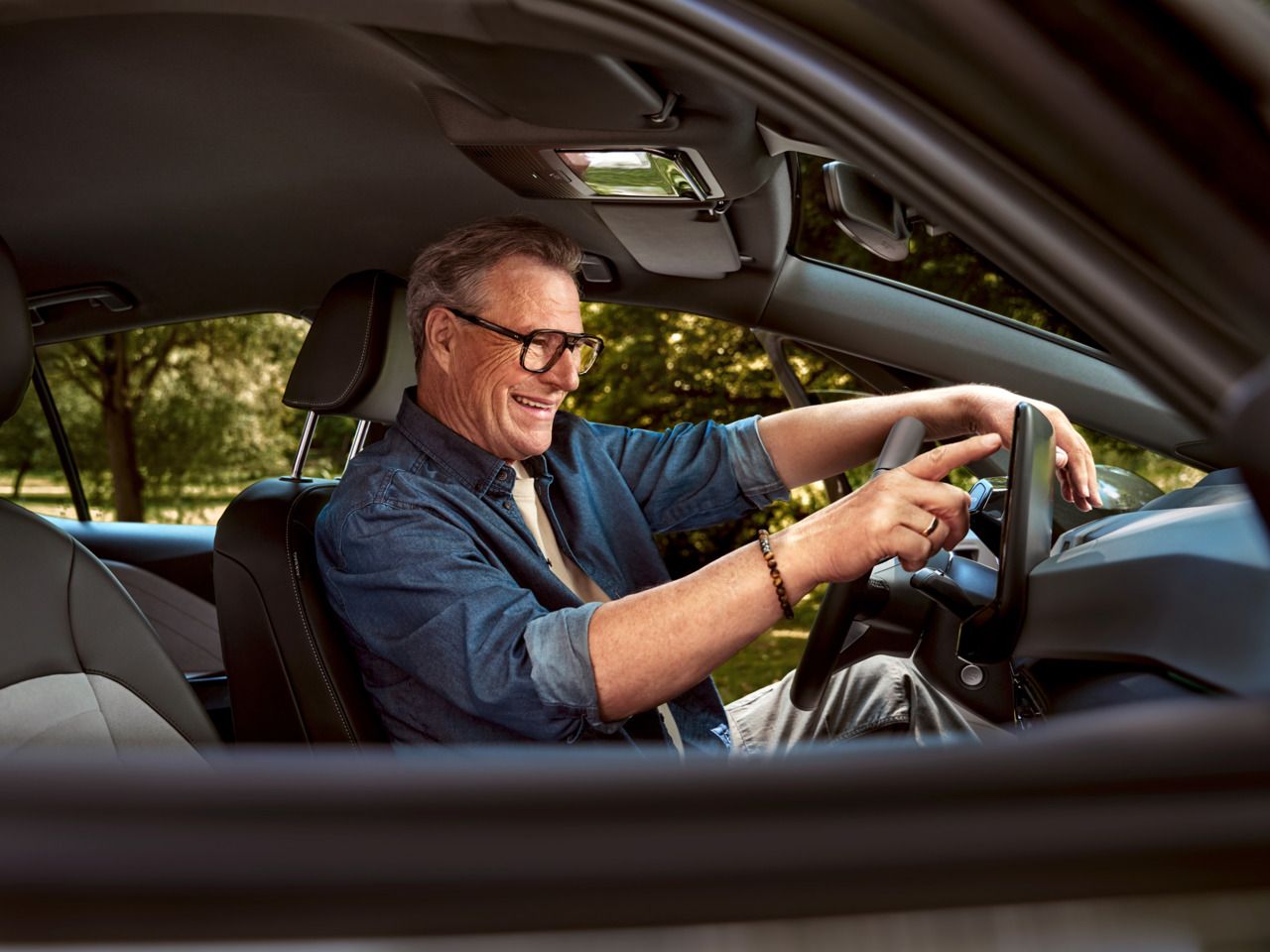 Ein Mann sitzt auf dem Fahrersitz seines geparkten ID.3 und tippt auf das HMI