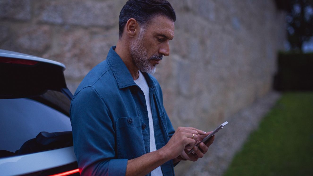Mann steht am Tayron und schaut auf sein Handy