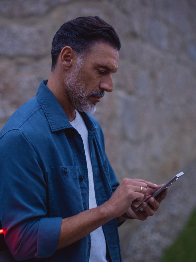 Mann steht am Tayron und schaut auf sein Handy