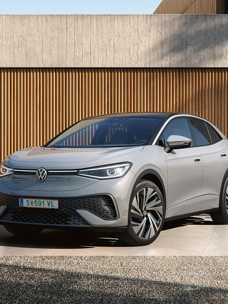 ID.5 Camouflage steht seitlich frontal in Parkhaus. Bäume im Hintergrund.