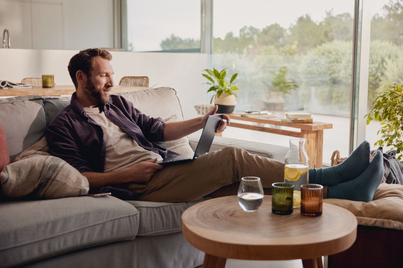Mann sitzt zu Hause und schaut auf ein Tablet