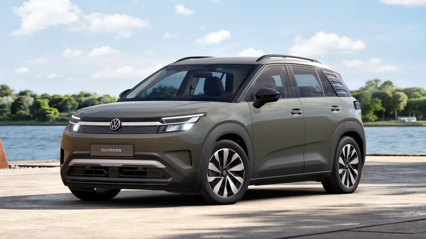 Ein olivgrüner VW ID. Cross Life mit modernem, kantigem Design steht auf einer Uferpromenade vor einem See. Im Hintergrund sind Wasser, Bäume und ein blauer Himmel mit vereinzelten Wolken zu sehen.