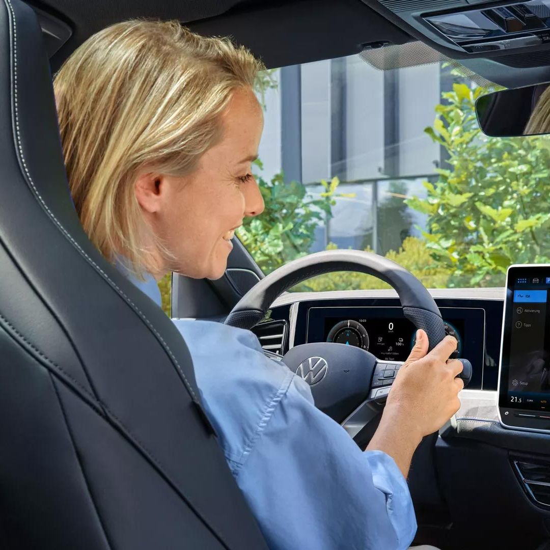 Eine Frau sitzt im VW Passat und blickt auf das Infotainmentsystem