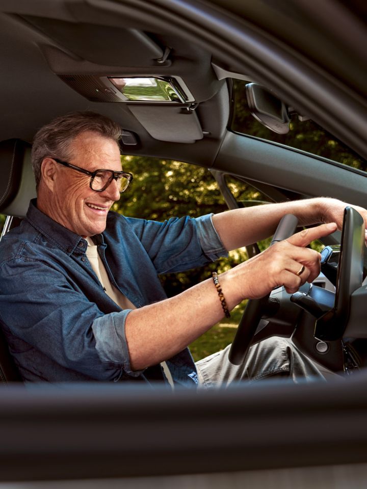Ein Mann sitzt auf dem Fahrersitz seines geparkten ID.3 und tippt auf das HMI