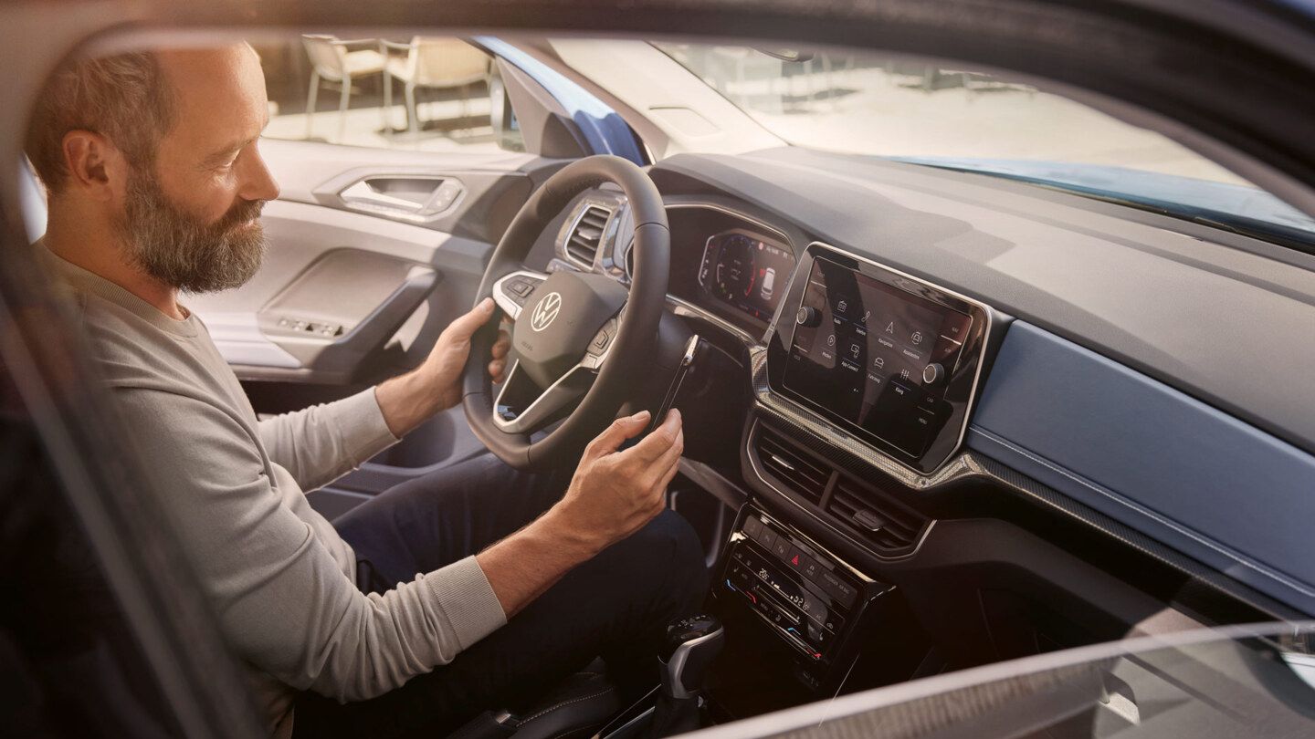 Blick durch das Beifahrerfenster, im VW T-Cross Style sitzt ein Mann.