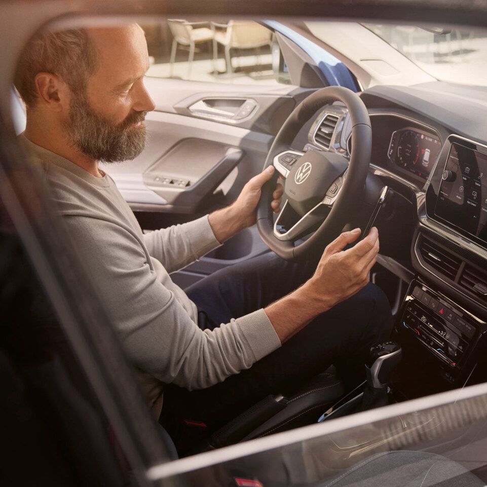 Blick durch das Beifahrerfenster, im VW T-Cross Style sitzt ein Mann.