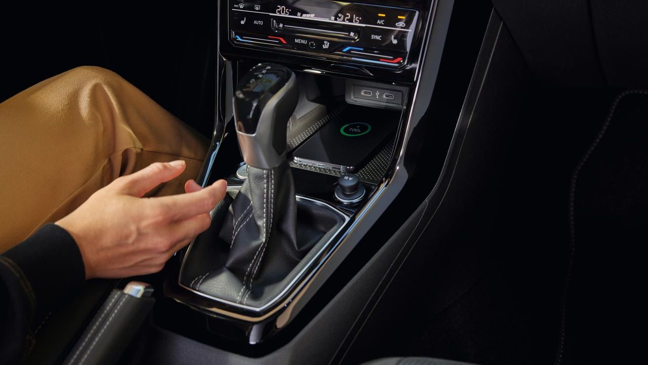 Ein Smartphone lädt im vordersten Fach der Mittelkonsole durch das Wireless Charging Pad im VW T-Cross.