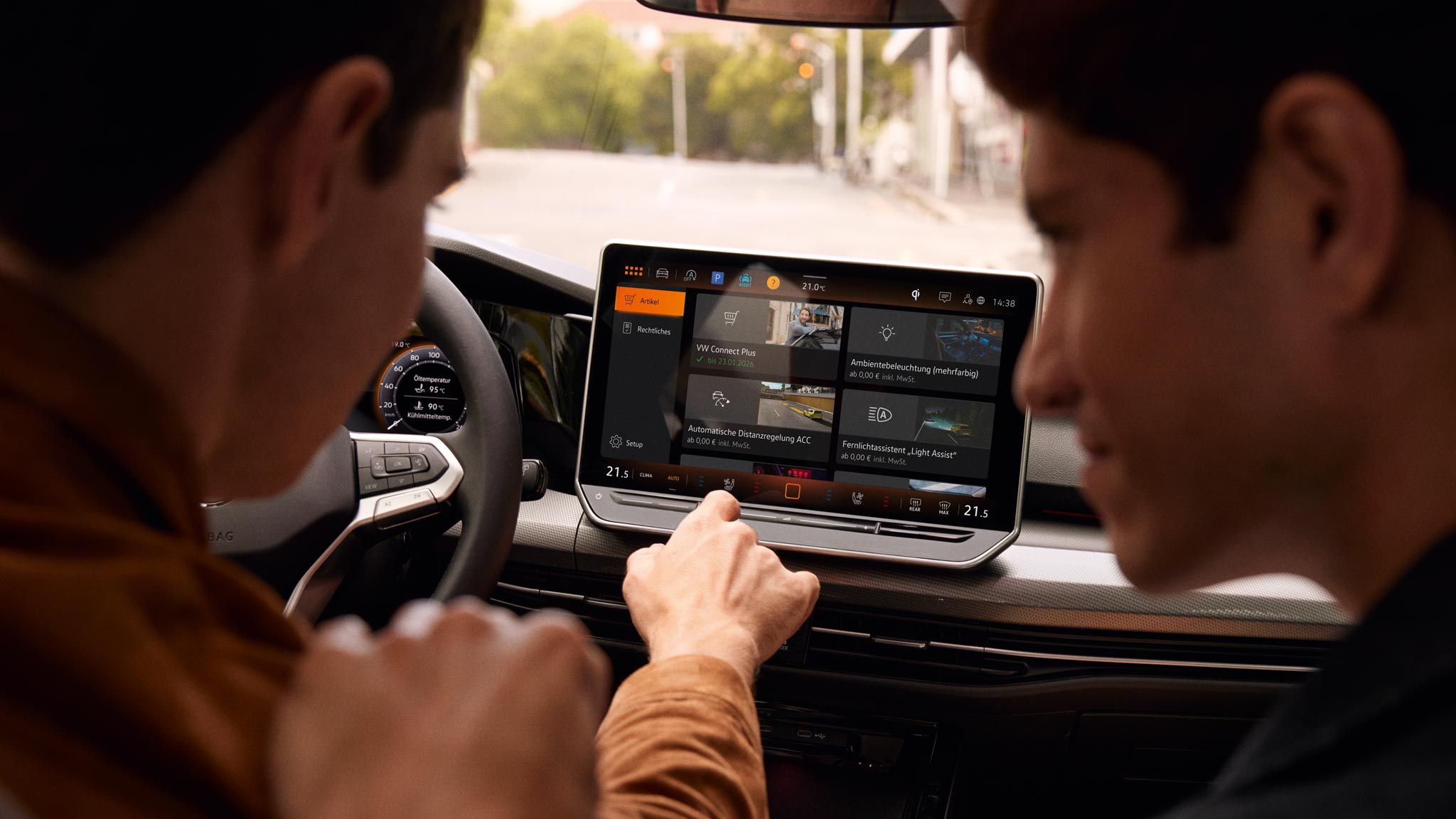 Zwei Männer sitzen im VW Golf und schauen auf das Infotainmentsystem 