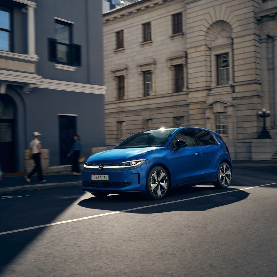 Ein blauer VW ID. Polo Style fährt durch eine Stadt.