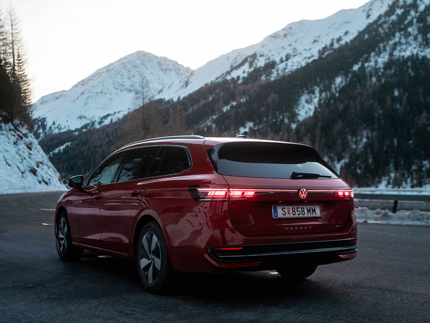 Ein roter VW Passat Elegance fährt an einer Landstraße in winterlicher Landschaft.