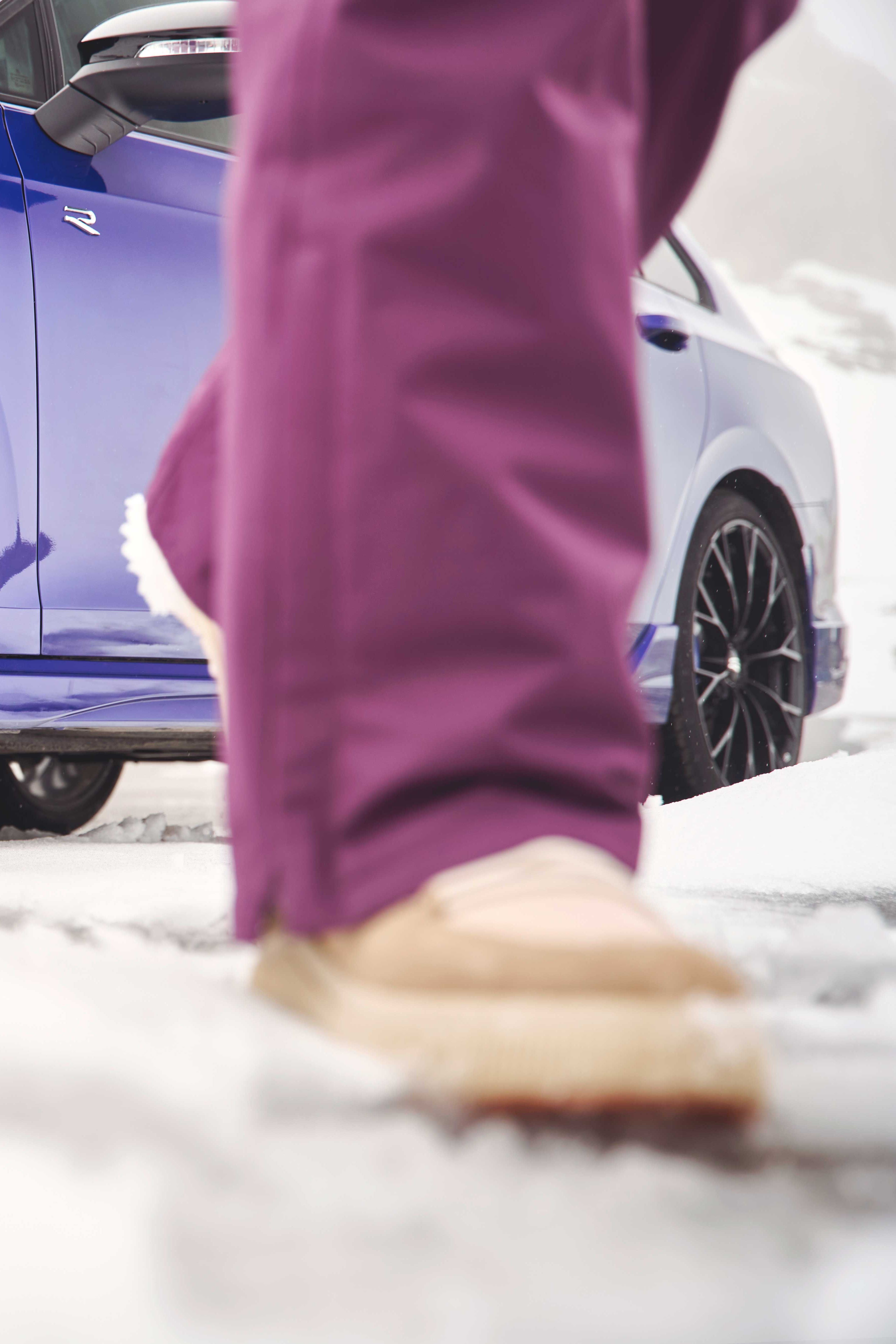 Fokusansicht der Winterkompletträder bei einem blauen Volkswagen Tayron. Im Vordergrund sind die Beine einer Person zu sehen.