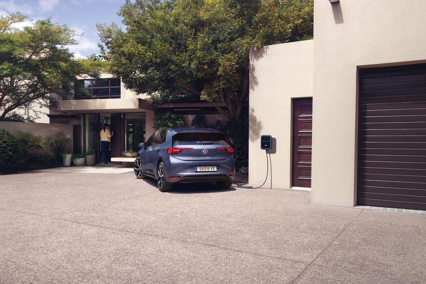 Ein blauer VW ID.3 Neo lädt an einer Wallbox vor einem Einfamilienhaus