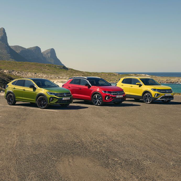 Taigo, T-Roc, T-Cross stehen geparkt auf einem Parkgelände, im Hintergrund sieht man das Meer.