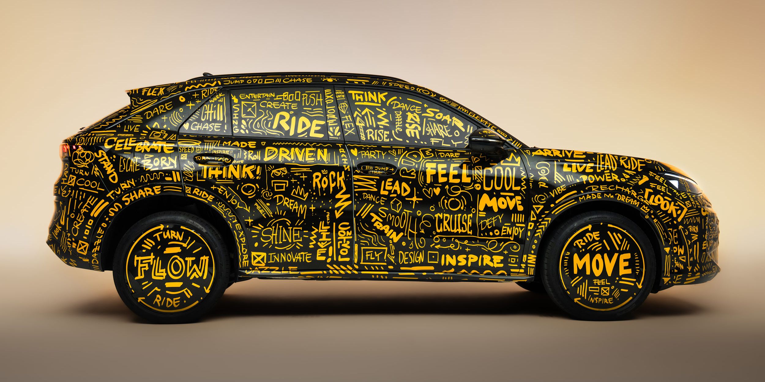 Der neue T-Roc, der vollständig mit gelben handgeschriebenen Worten und Illustrationen bedeckt ist. Die Wörter umfassen positive und inspirierende Begriffe wie "Flow", "Move" und "Inspire". Das Fahrzeug steht vor einem hellbraunen Hintergrund.