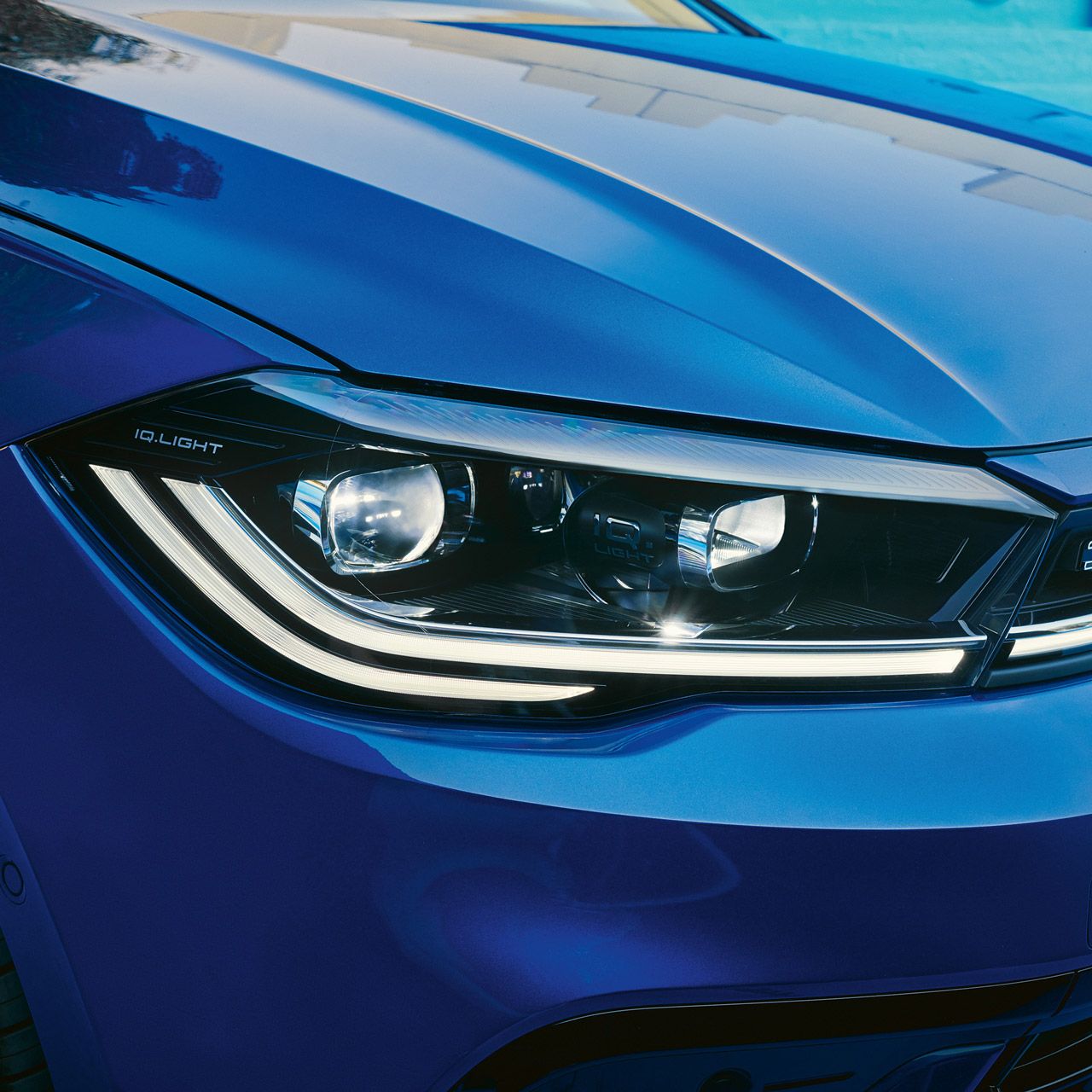 Detailansicht der Front-Lichtsignatur eines blauen VW Polo.