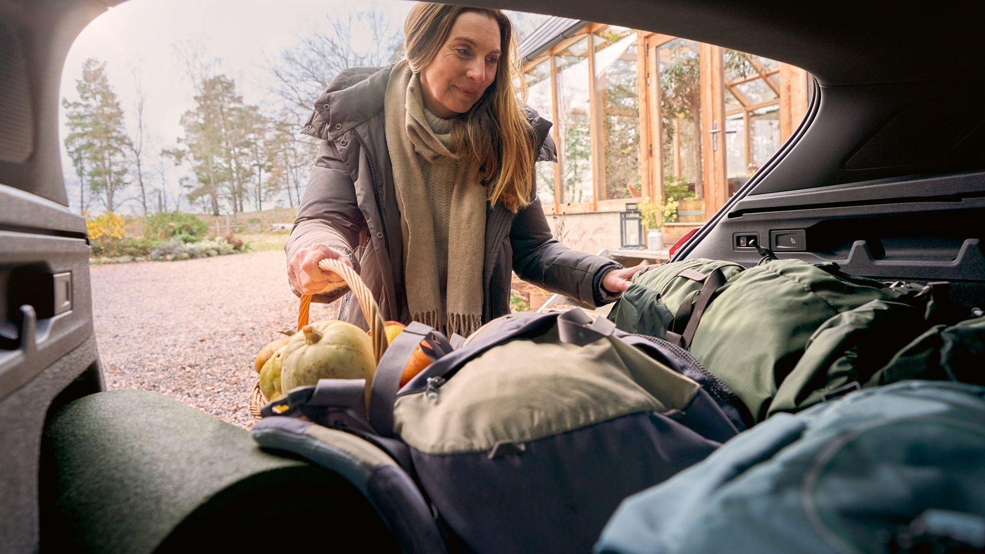 Eine Frau legt ihr Gepäck in den Kofferraum des VW ID.7 GTX Tourer.