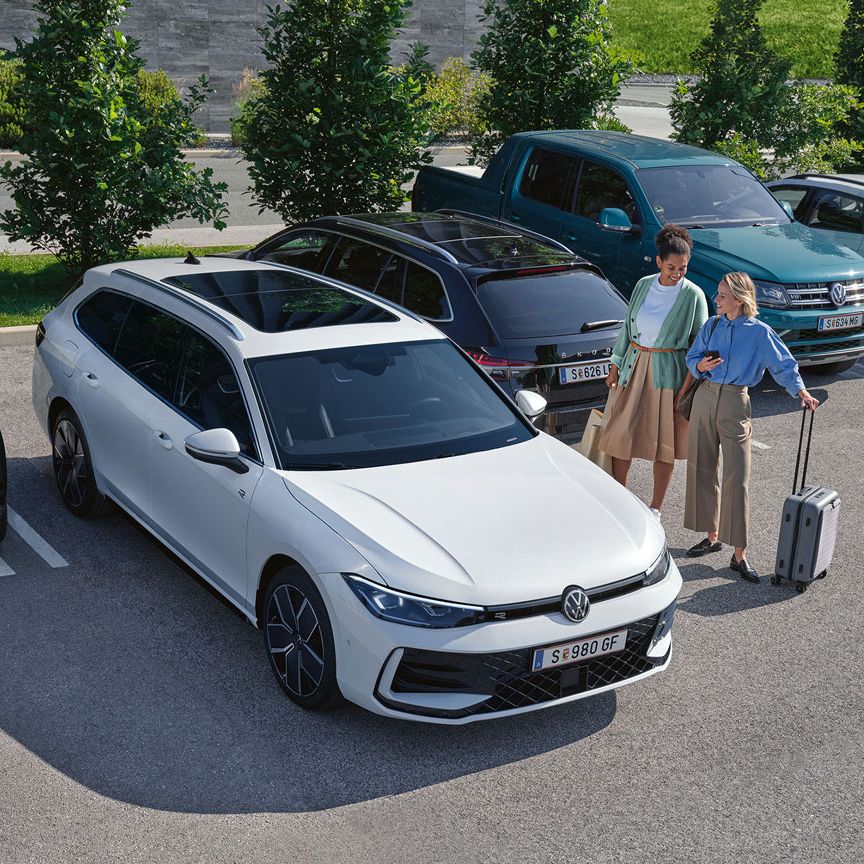 Zwei Frauen stehen auf einem Parkplatz neben einem weißen VW Passat, der per 